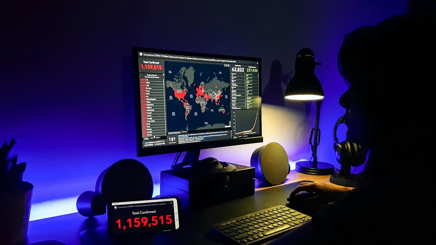 A person analyzes global health data on multiple digital screens.